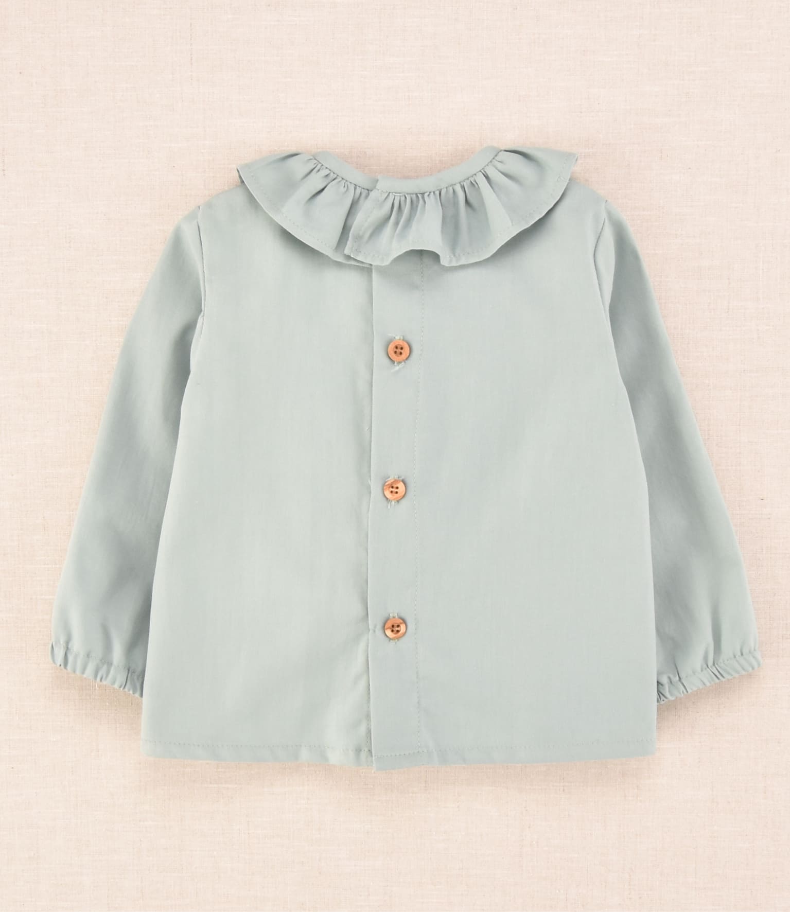 Espalda de blusa de bebé verde agua con botones de madera, colección Cocote x Charanga