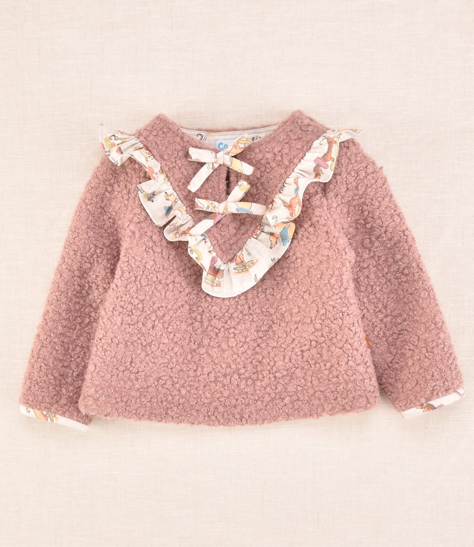 Jersey de bebé en color rosa empolvado con volantes estampados y lazo delantero de Cocote x Charanga