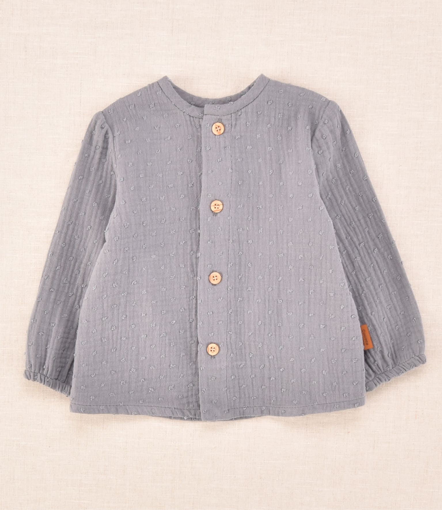 Blusa de bebé unisex gris con textura plumeti y botones delanteros de madera | Cocote x Charanga