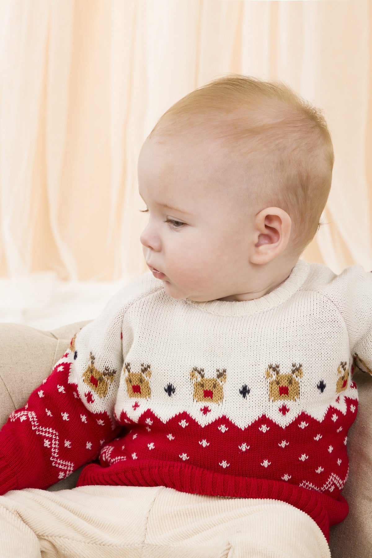 Bebé recién nacido sentado con jersey navideño multicolor con renos, foto lifestyle interior Charanga